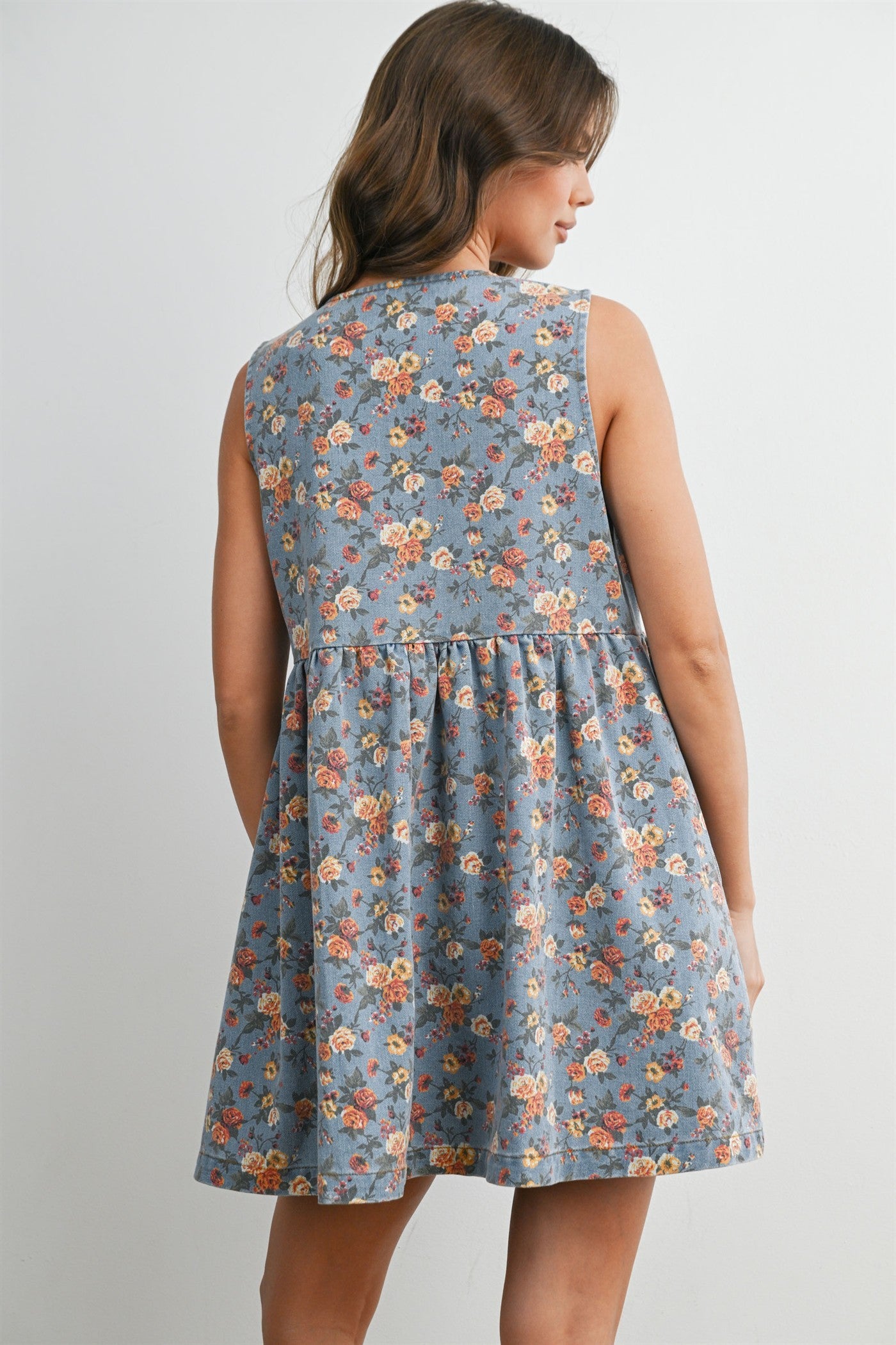 woman wearing a blue floral sleeveless dress with a flared skirt, shown from the back