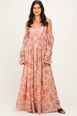 woman wearing a pink floral off-the-shoulder maxi dress with puffed sleeves and a relaxed fit