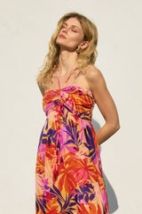 woman wearing a vibrant floral print halter dress with a knotted bodice and loose fit