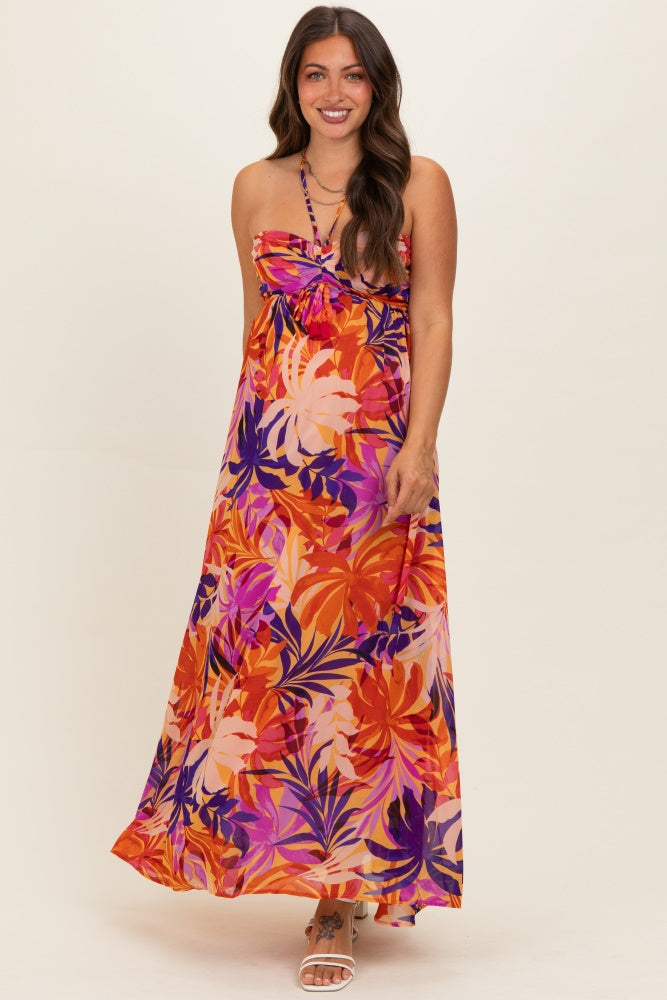 woman wearing a colorful floral maternity maxi dress with a bow detail and spaghetti straps, showcasing her baby bump