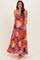 woman wearing a colorful floral maternity maxi dress with a bow detail and spaghetti straps, showcasing her baby bump