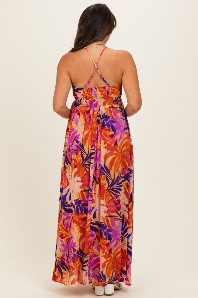 woman wearing a vibrant floral maternity maxi dress with a smocked back and adjustable straps.