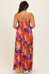 woman wearing a vibrant floral maternity maxi dress with a smocked back and adjustable straps.