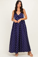woman wearing a navy blue polka dot maxi dress with a tie detail at the bust and a flowing skirt
