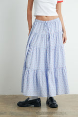 woman wearing a light blue tiered maxi skirt with red and navy floral prints and black loafers