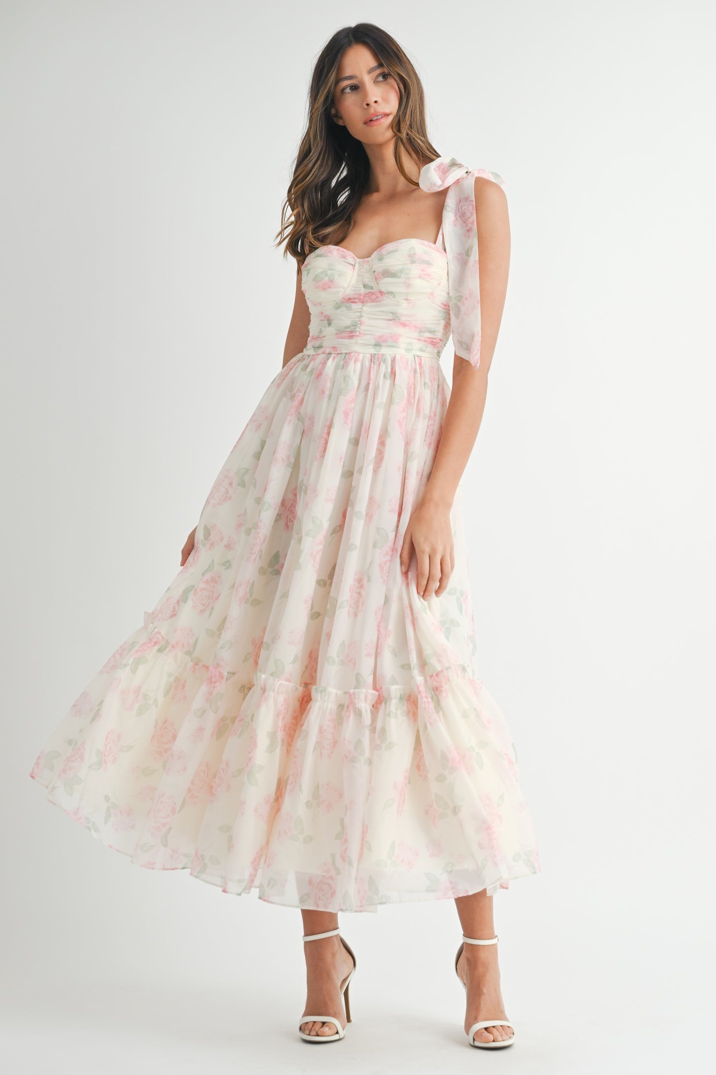 woman wearing a floral print pastel maxi dress with a sweetheart neckline and bow tie straps