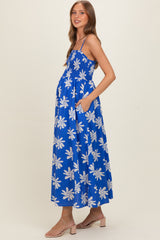 woman wearing a blue floral maternity maxi dress with a smocked bodice and pockets, showing her baby bump