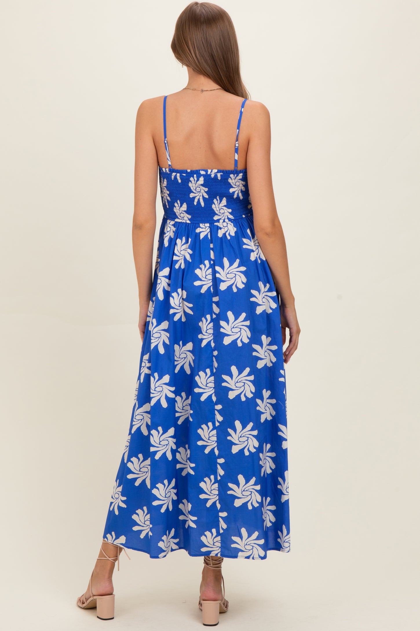 woman wearing a blue floral maternity maxi dress with adjustable straps and a smocked back view