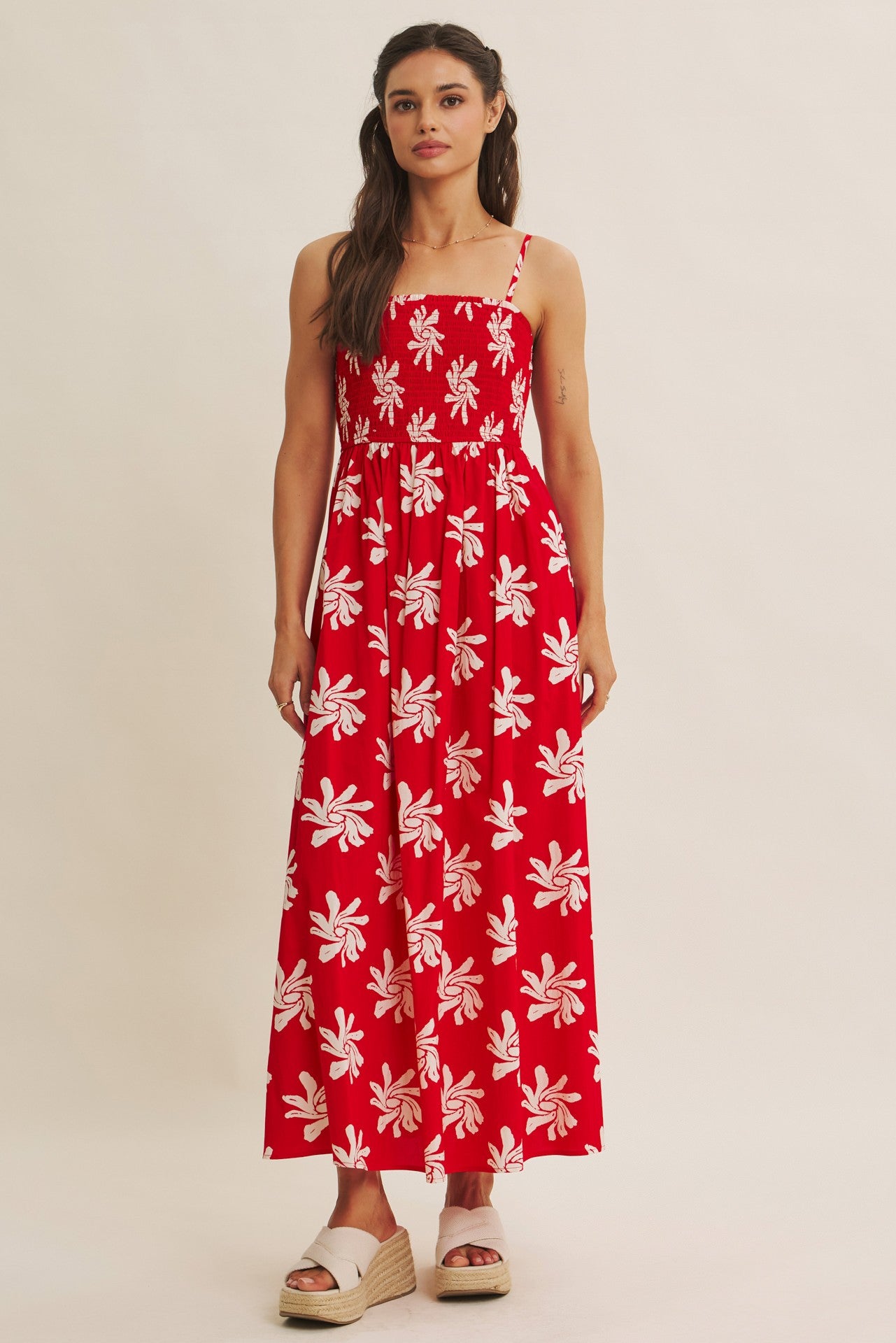 woman wearing a red floral print maxi dress with a square neckline and spaghetti straps