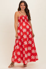 woman wearing a red floral maternity maxi dress with adjustable straps and a fitted bodice, smiling at the camera