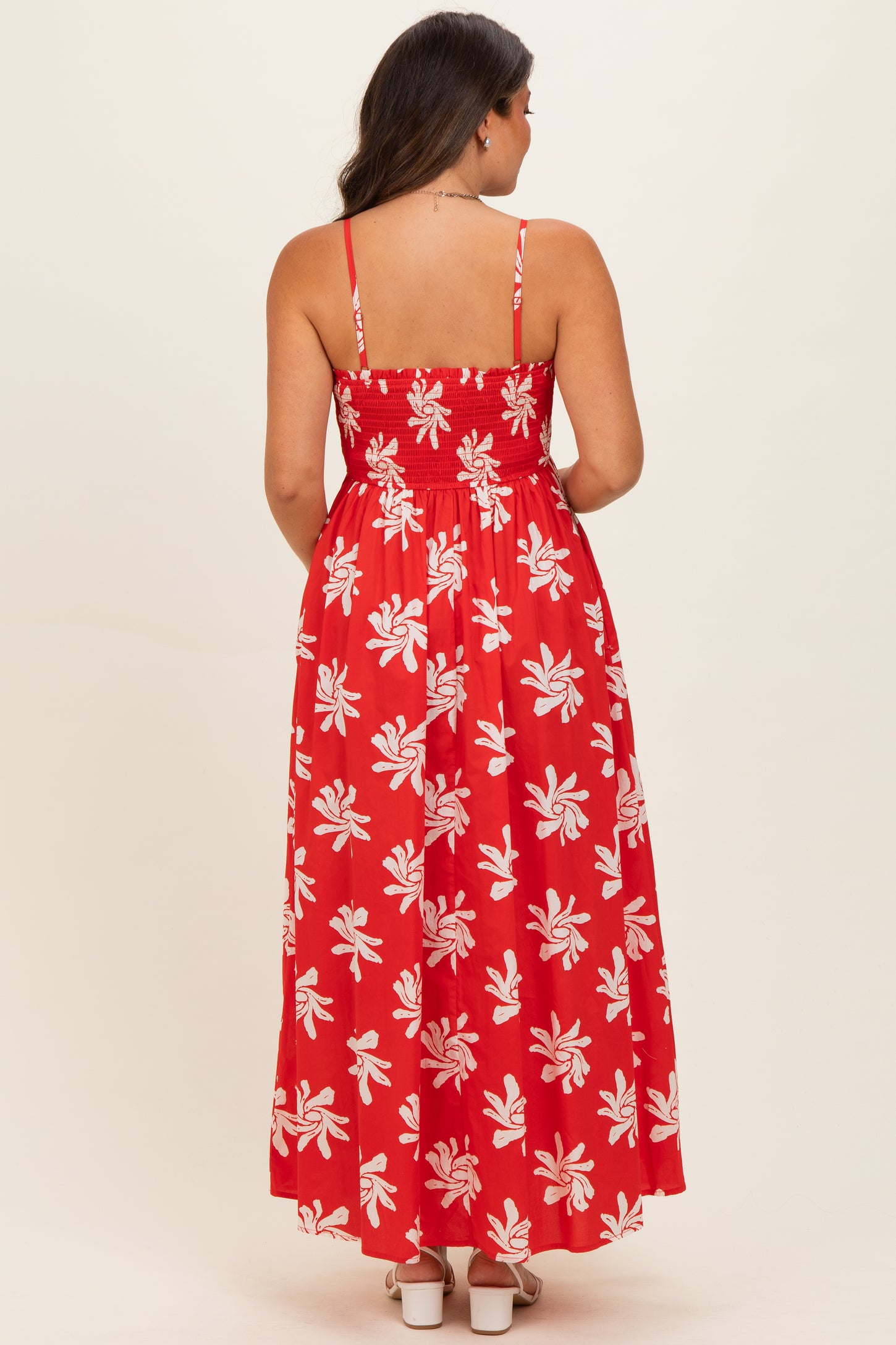 woman wearing a red maternity maxi dress with a floral pattern and back smocking detail