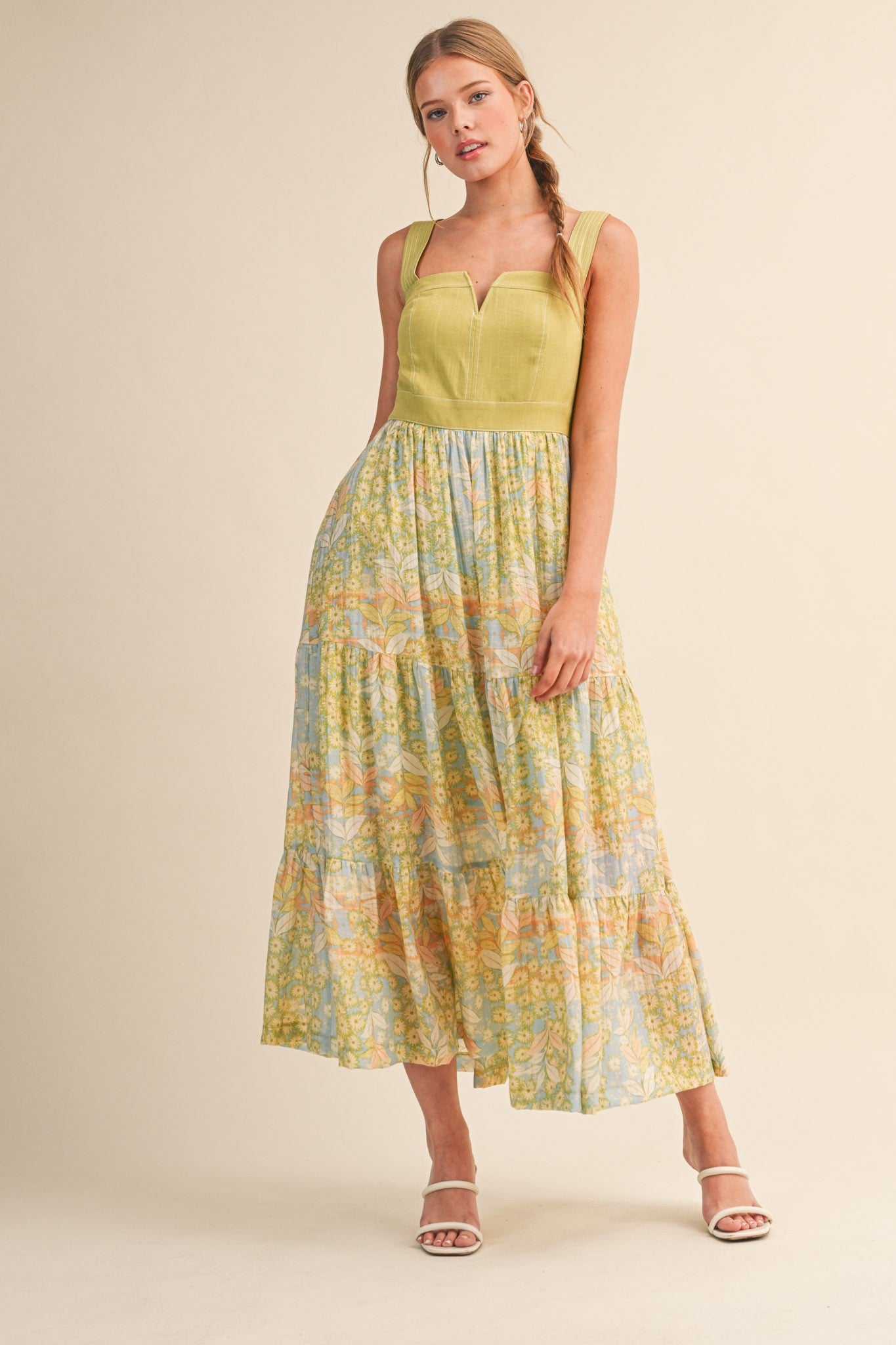 woman wearing a green and pastel patterned tiered maxi dress with a sweetheart neckline and spaghetti straps