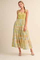 woman wearing a green and pastel patterned tiered maxi dress with a sweetheart neckline and spaghetti straps