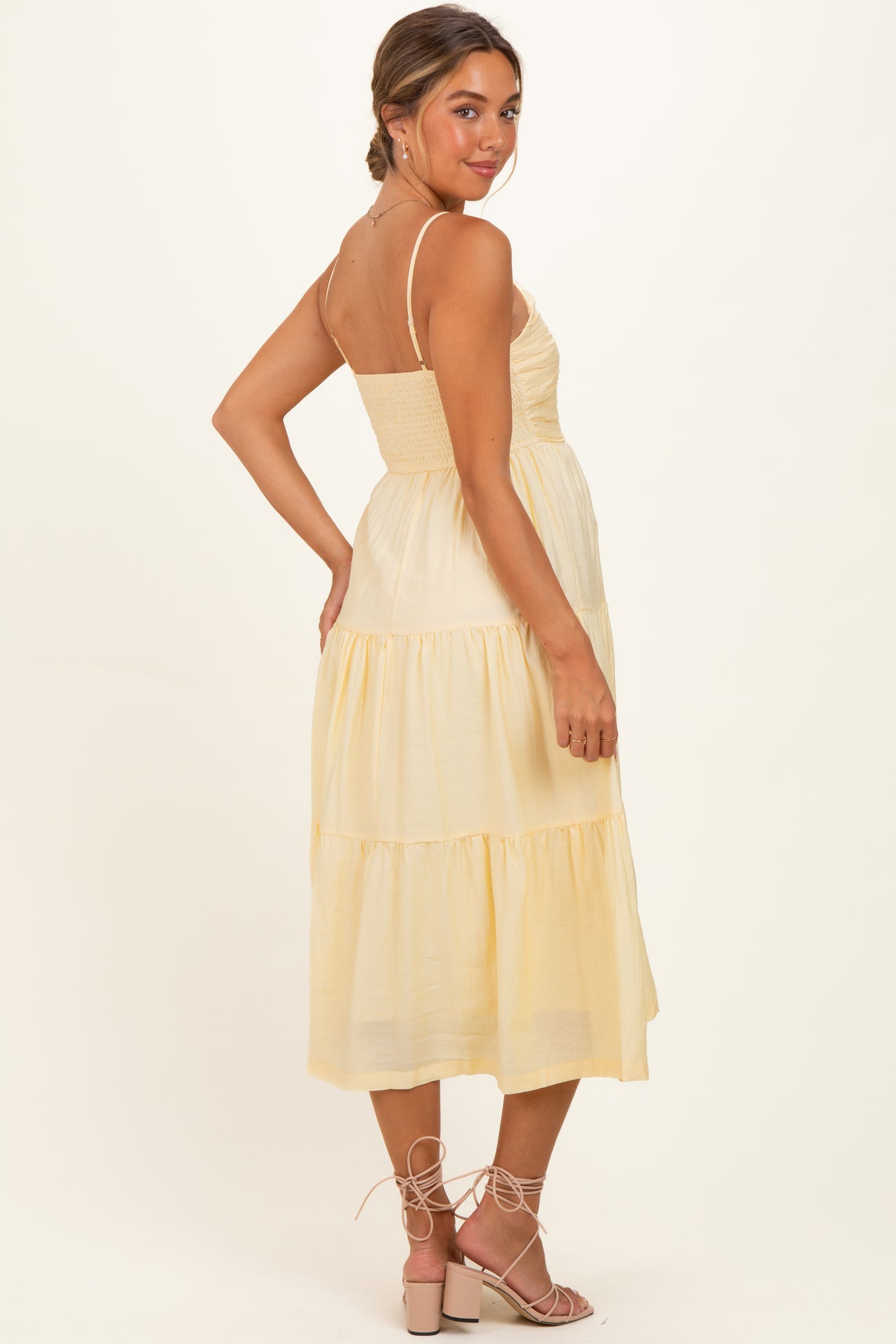 woman wearing a light yellow maternity maxi dress with a smocked bodice and tiered skirt, showing her baby bump