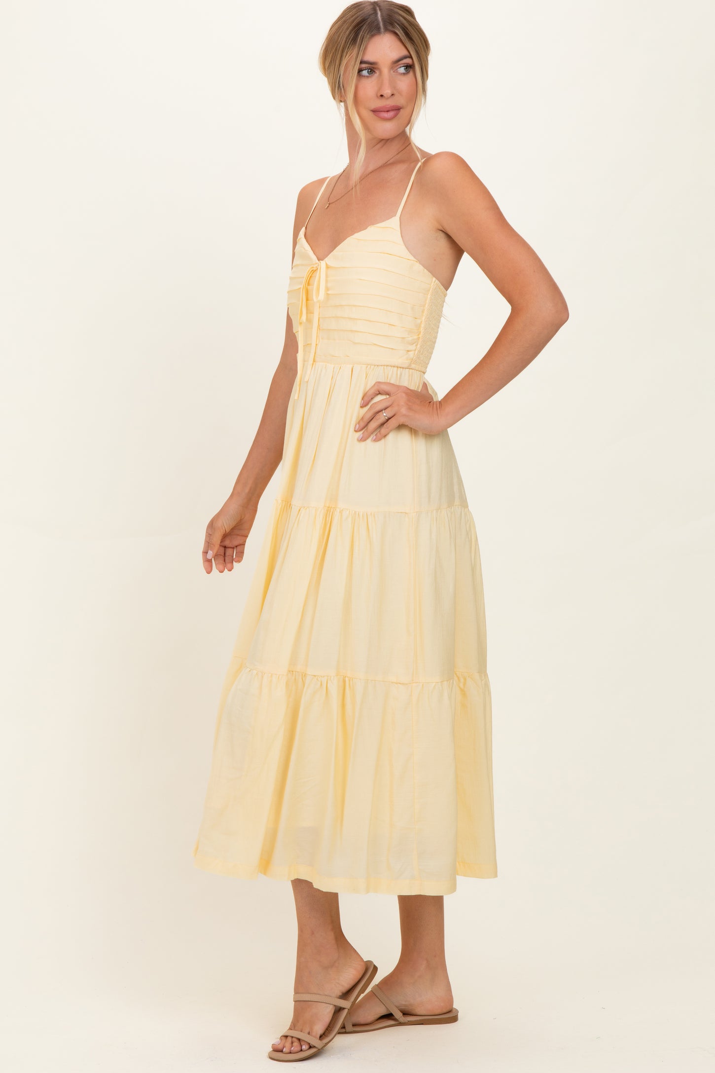 woman wearing a light yellow tiered maxi dress with adjustable spaghetti straps and a gathered bodice