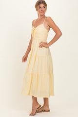 woman wearing a light yellow tiered maxi dress with adjustable spaghetti straps and a gathered bodice