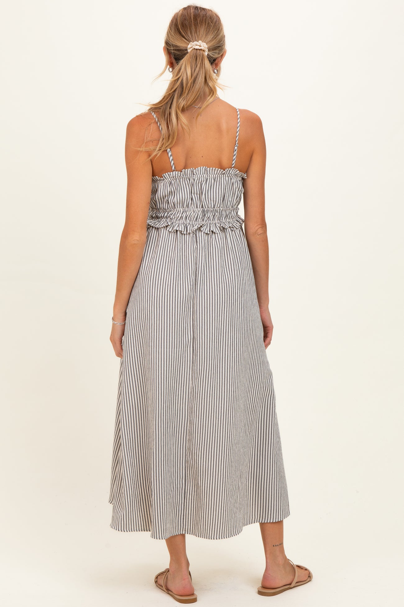 woman wearing a black and white striped maternity maxi dress with a smocked bodice and adjustable straps