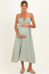 woman wearing a green and white striped maternity dress with tie-front detail and holding her baby bump