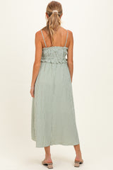 woman wearing a green and white striped maternity maxi dress with a smocked back and adjustable spaghetti straps