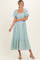 woman wearing a light mint green midi dress with puff sleeves and ruffle hem