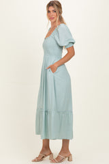 woman wearing a light blue puff sleeve maxi dress with smocked bodice and pockets