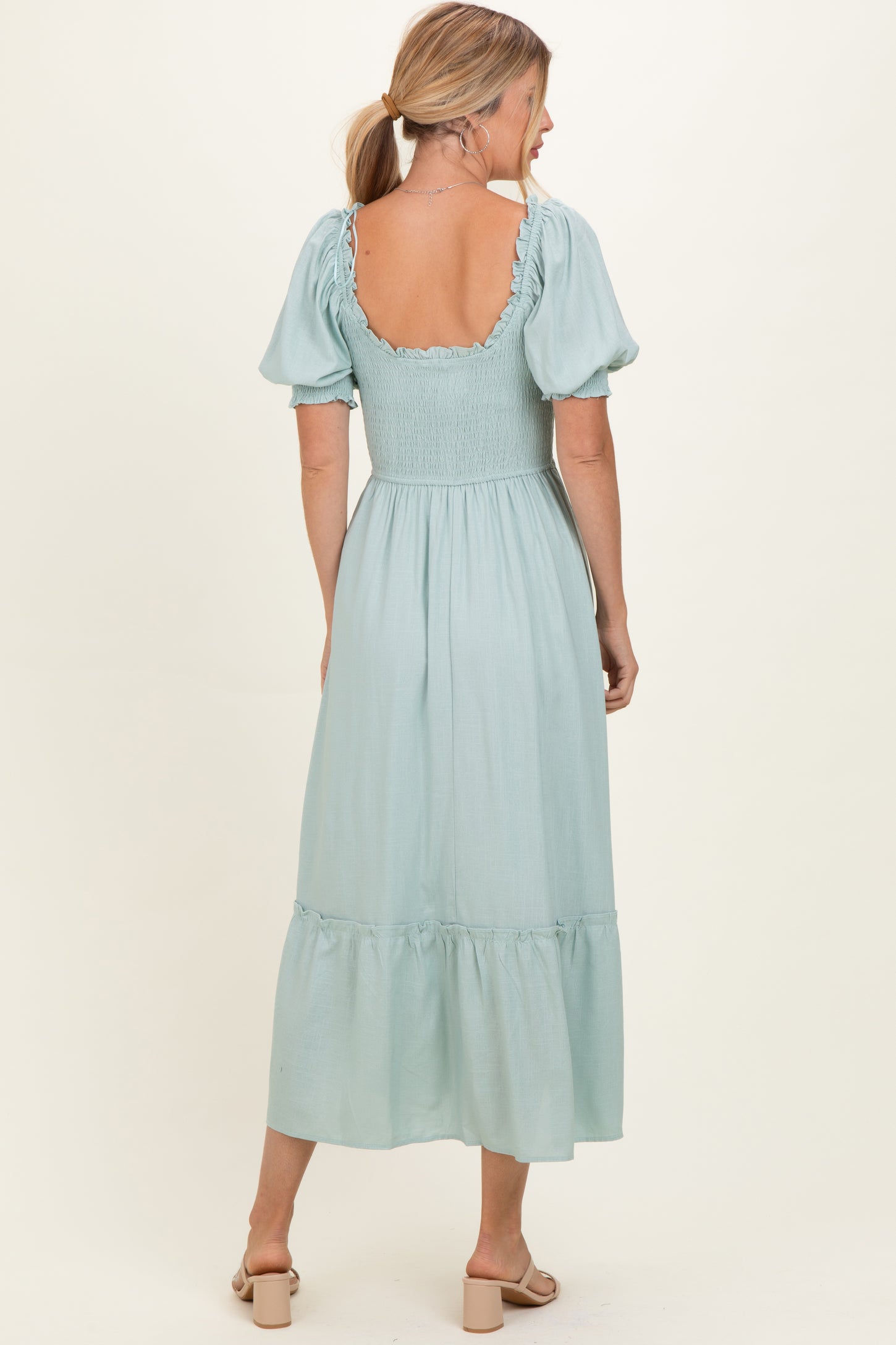 woman wearing a mint green puff sleeve maxi dress with a smocked bodice and tiered skirt, seen from the back