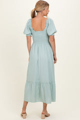 woman wearing a mint green puff sleeve maxi dress with a smocked bodice and tiered skirt, seen from the back