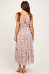 woman wearing a light pink floral maternity maxi dress with a plunging back and tie straps