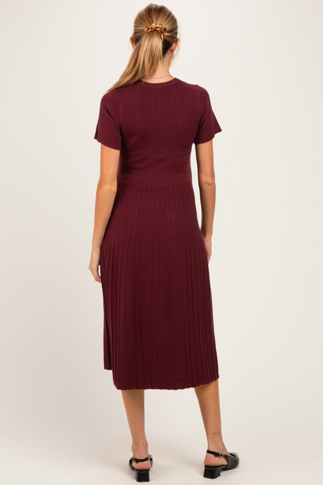 woman wearing a burgundy ribbed short sleeve maternity dress with a fitted silhouette and midi length