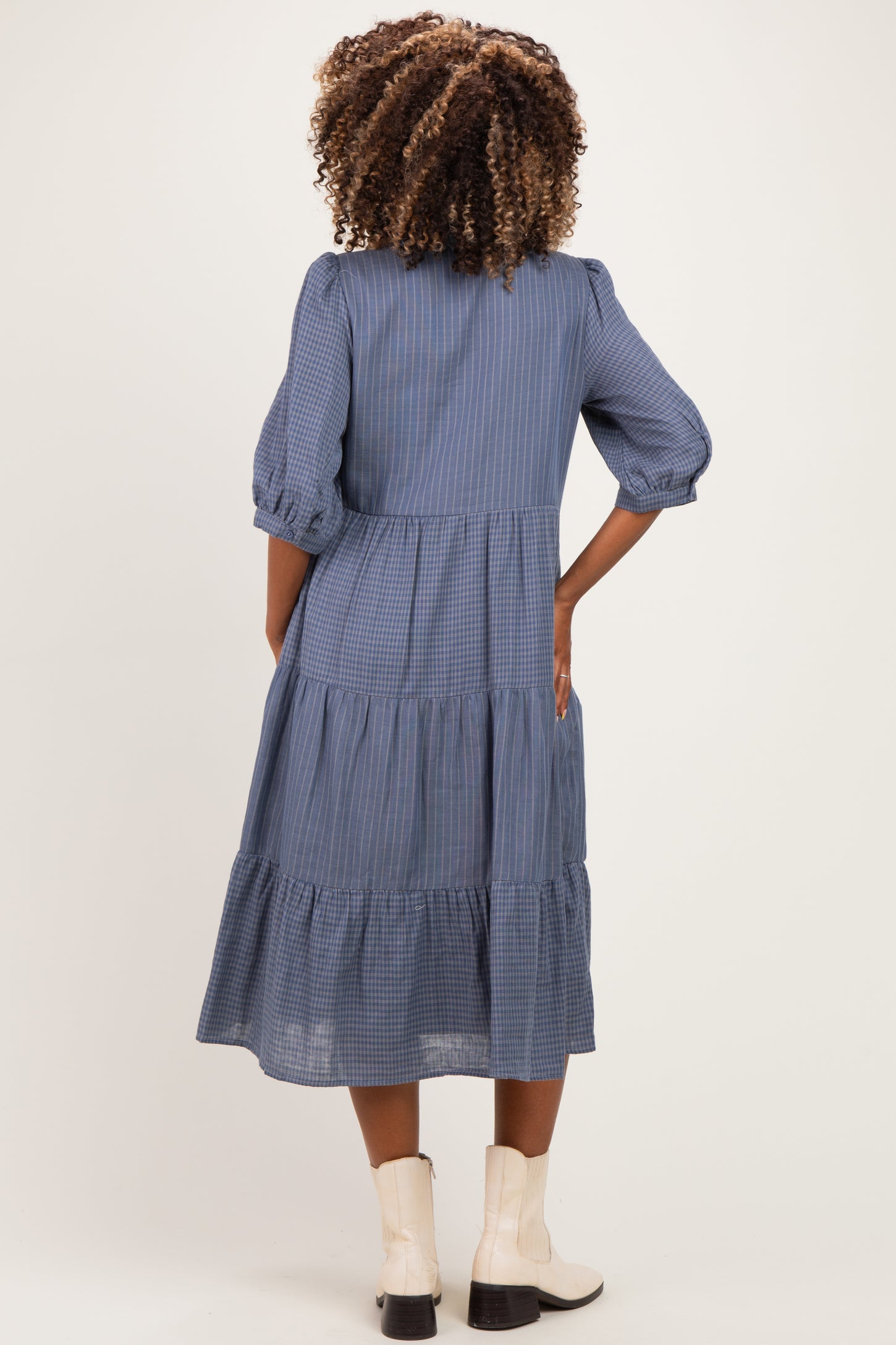 woman wearing a blue striped maternity dress with puff sleeves and tiered skirt, showing her back view