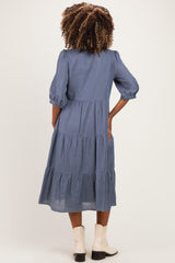 woman wearing a blue striped maternity dress with puff sleeves and tiered skirt, showing her back view