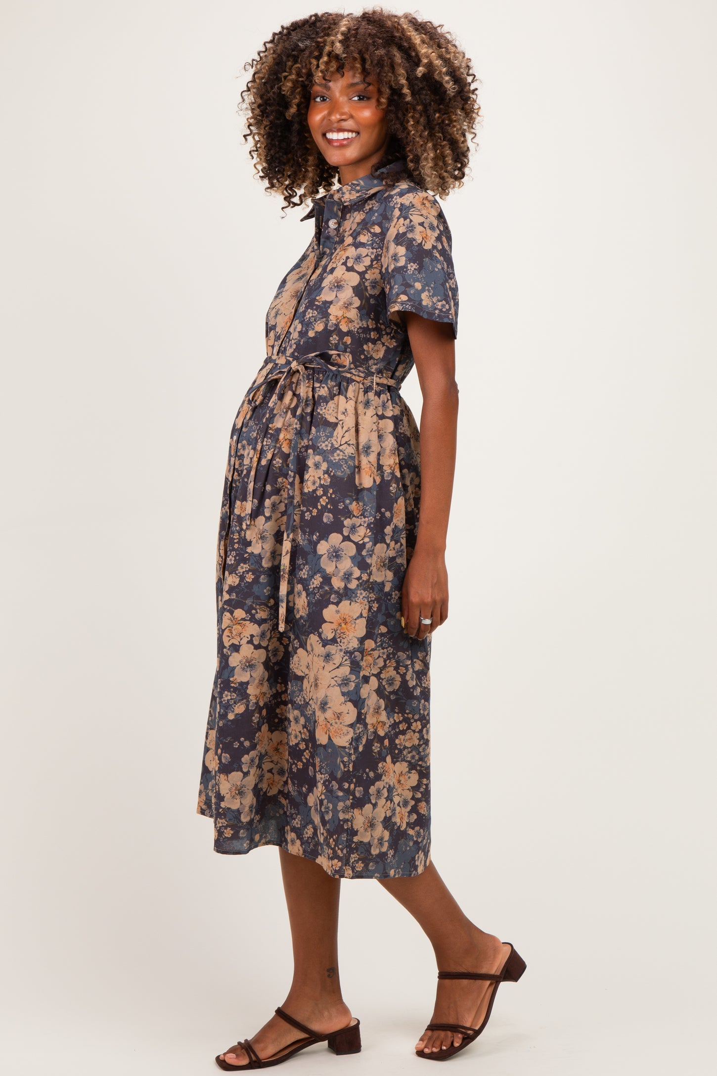 woman wearing a navy blue floral maternity dress with short sleeves and a tie waist, showing her baby bump