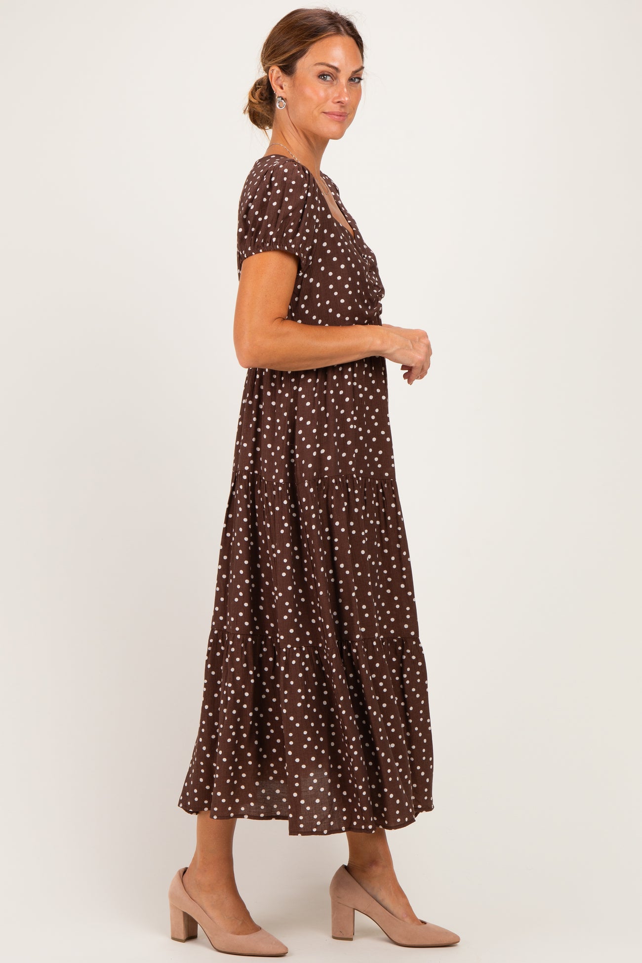 woman wearing a brown polka dot maxi dress with short sleeves and a tiered skirt, styled with nude heels