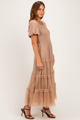 woman wearing a beige puff sleeve maxi dress with tiered tulle skirt and a smocked bodice, standing sideways