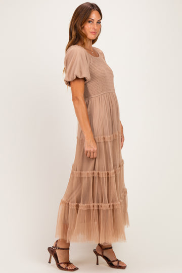 woman wearing a beige puff sleeve maxi dress with tiered tulle skirt and a smocked bodice, standing sideways