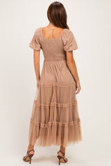 woman wearing a beige maxi dress with puff sleeves and tiered tulle skirt, showing the back view