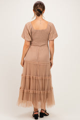 woman wearing a beige maternity dress with a smocked bodice and tiered tulle skirt, showing the back view