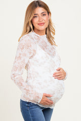 woman wearing a white floral long sleeve maternity top and cradling her baby bump