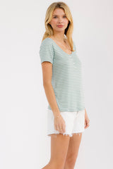 woman wearing a green and white striped short sleeve button-up top with white denim shorts