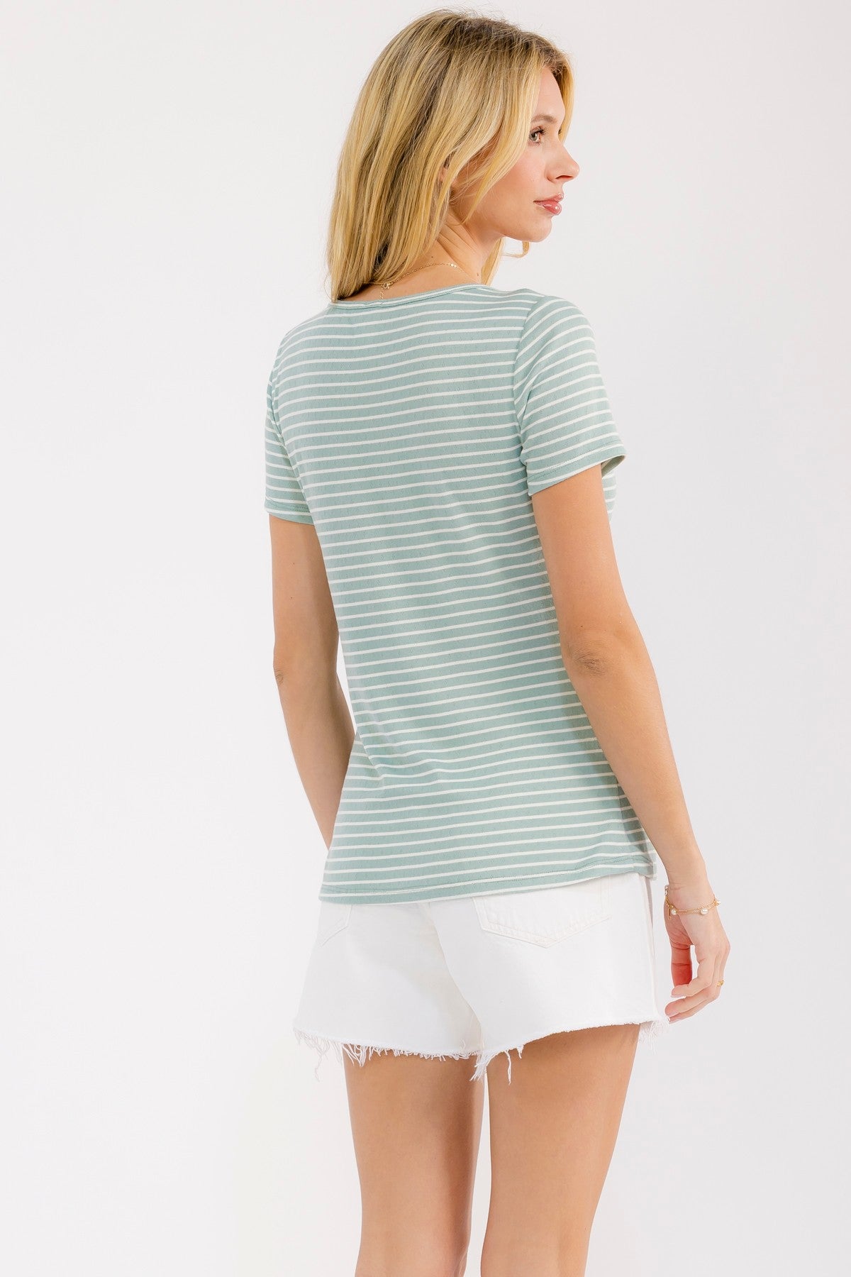 woman wearing a light green striped t-shirt with a crew neckline and short sleeves, paired with white shorts