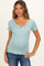 woman wearing a light teal striped maternity top with short sleeves and a henley neckline, showing a baby bump