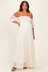 woman wearing a white off-the-shoulder lace maternity maxi dress with puff sleeves and a fitted bodice