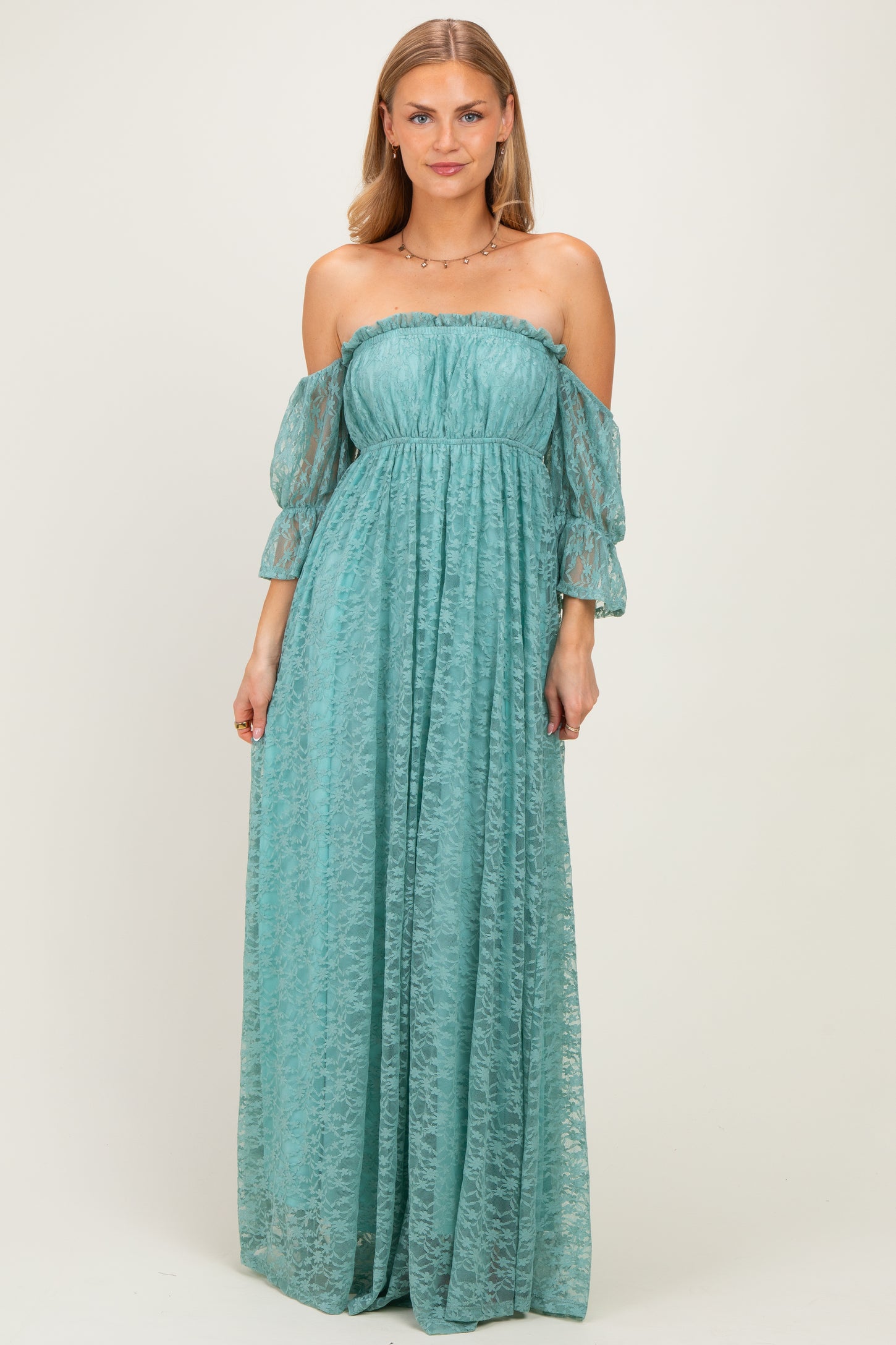 woman wearing a teal off-the-shoulder maxi dress with long puff sleeves and a flowing skirt