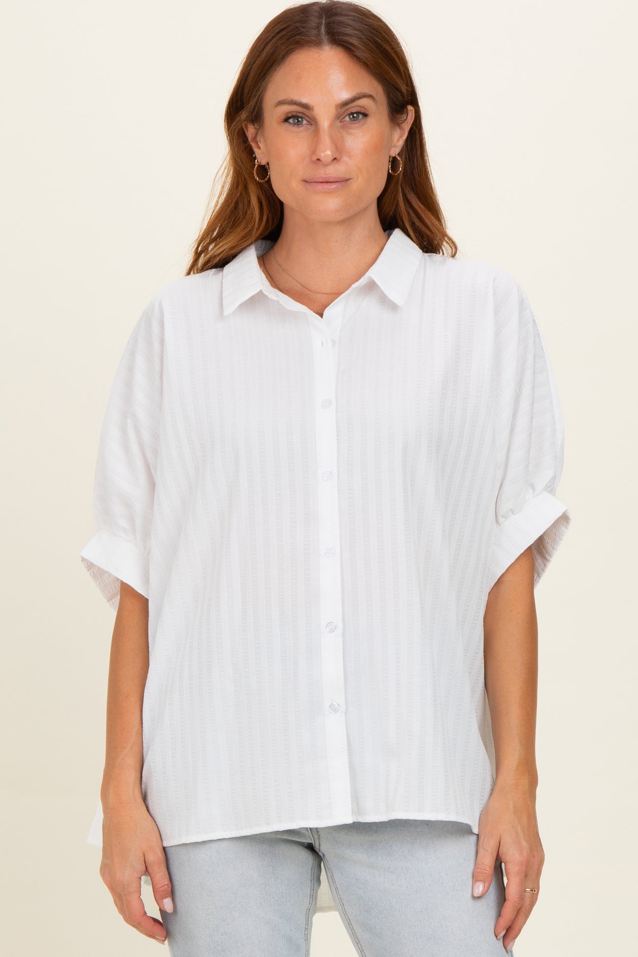 woman wearing a white short sleeve button-up blouse with a relaxed fit and subtle stripe detail
