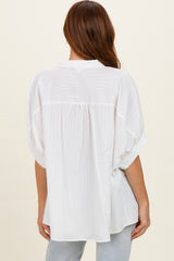 woman wearing a white oversized button-up shirt with a relaxed fit and short rolled sleeves, viewed from the back