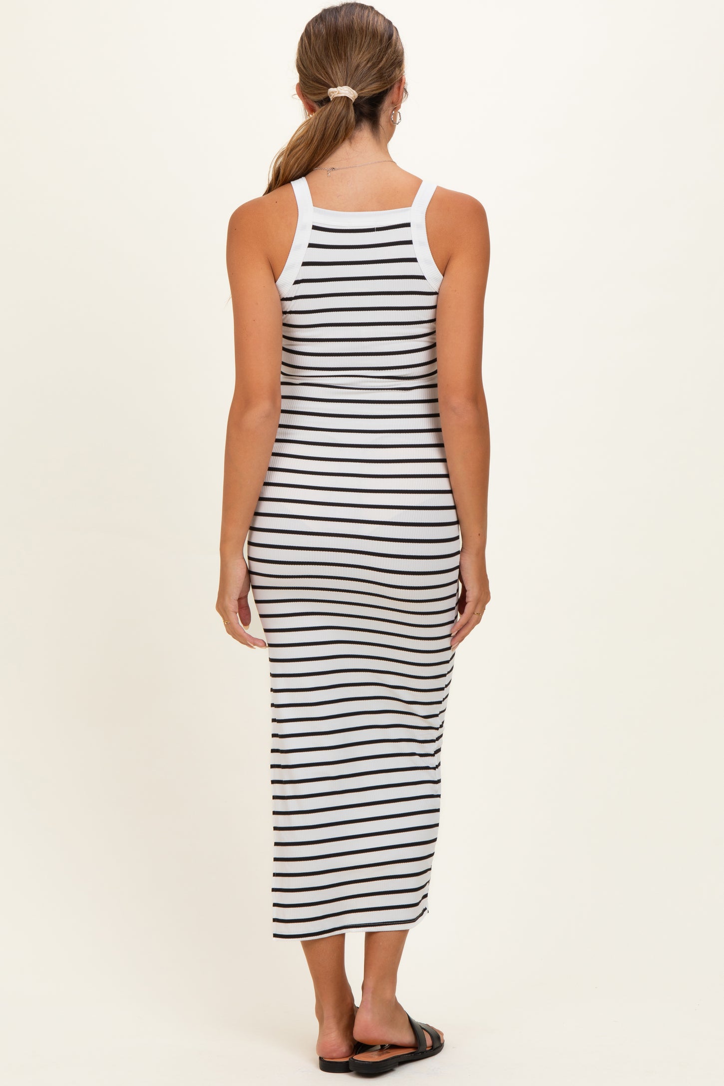 woman wearing a black and white striped maternity maxi dress, viewed from the back