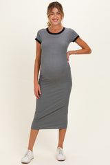 woman wearing a gray maternity dress with black trim and a visible baby bump, standing in white sneakers