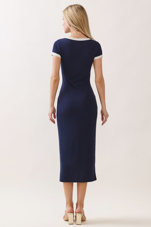 woman wearing a navy blue fitted midi dress with short sleeves and white trim, shown from the back