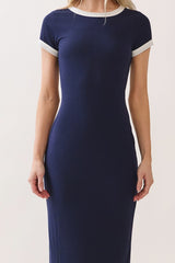 woman wearing a navy blue ribbed maxi dress with white trim on the sleeves