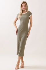 woman wearing a fitted olive green midi dress with white trim and short sleeves, standing in a relaxed pose